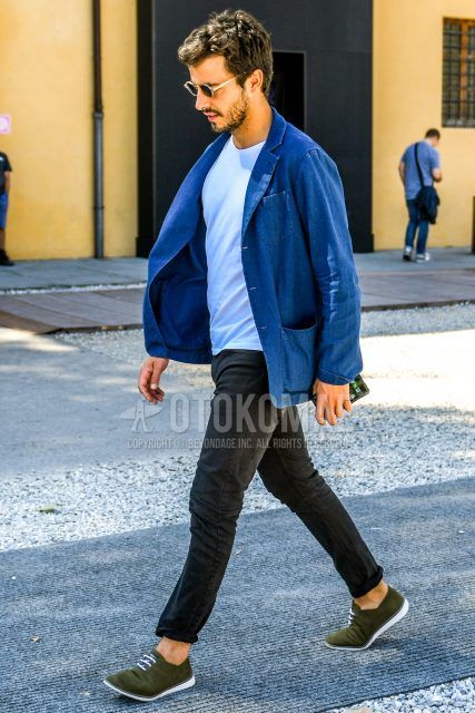 A men's spring/summer/fall outfit for men with plain sunglasses, plain blue tailored jacket, plain white t-shirt, plain black denim/jeans, and olive green or other leather shoes.