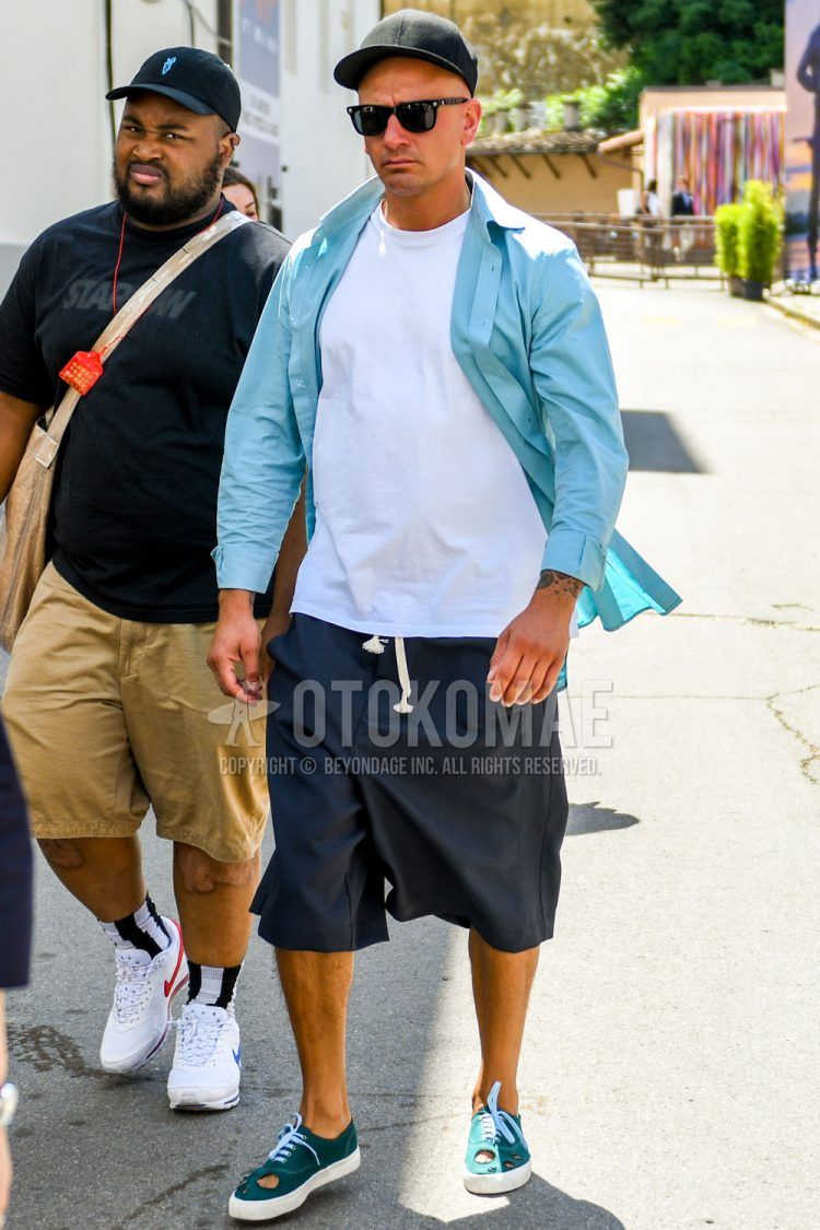 A spring/summer men's coordinate outfit with solid color others, solid color sunglasses, solid color blue shirt, solid color white t-shirt, solid color navy shorts, and green low-cut sneakers.