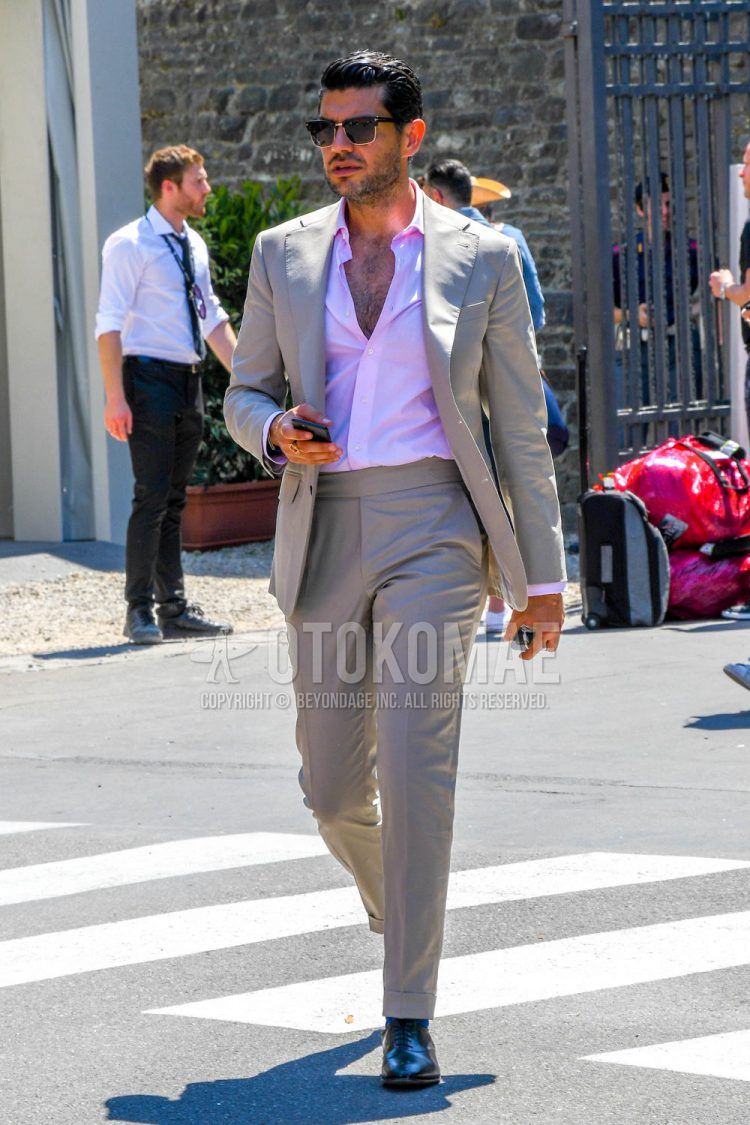A men's spring, summer, and fall outfit with plain sunglasses, a plain pink shirt, black straight tip leather shoes, and a plain beige suit.