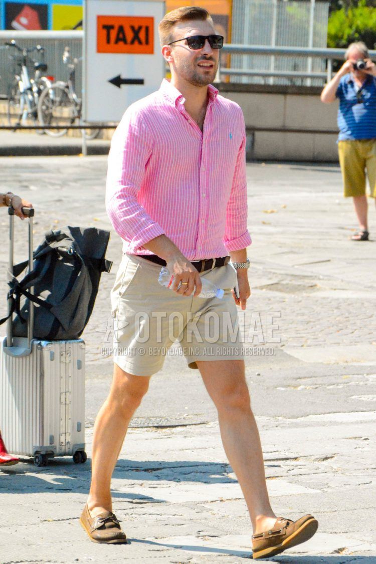 A spring/summer men's coordinate outfit with plain sunglasses, pink striped shirt, plain leather belt, plain beige shorts, and brown moccasin/deck shoe leather shoes.