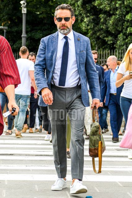 Spring, summer, and fall men's coordinate outfit with plain silver sunglasses, light blue and other tailored jacket, plain white shirt, plain brown suspenders, plain gray slacks, white low-cut sneakers, and plain blue knit tie.