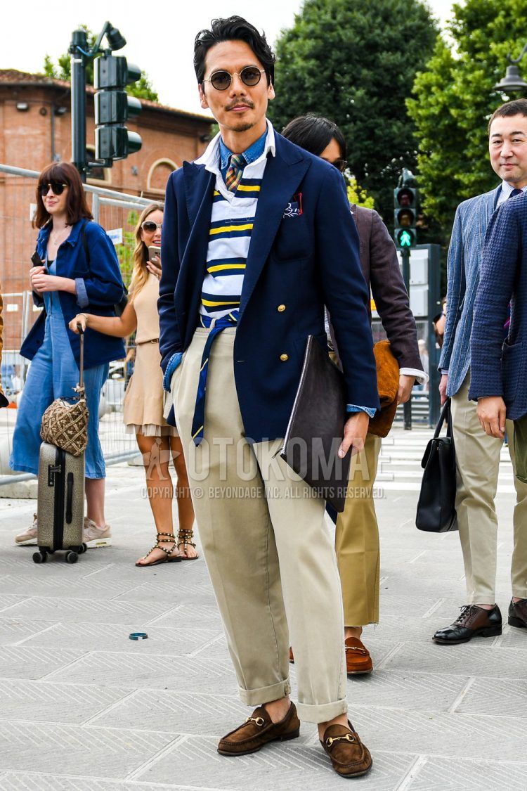 Solid color sunglasses, solid color navy tailored jacket, solid color navy denim/chambray shirt, yellow and white striped polo shirt, navy striped tape belt, solid color beige cotton pants, brown bit loafer leather shoes, solid color black clutch bag/second bag/drawstring, and a multi-colored checkered tie, a spring/summer/fall men's coordinate outfit.
