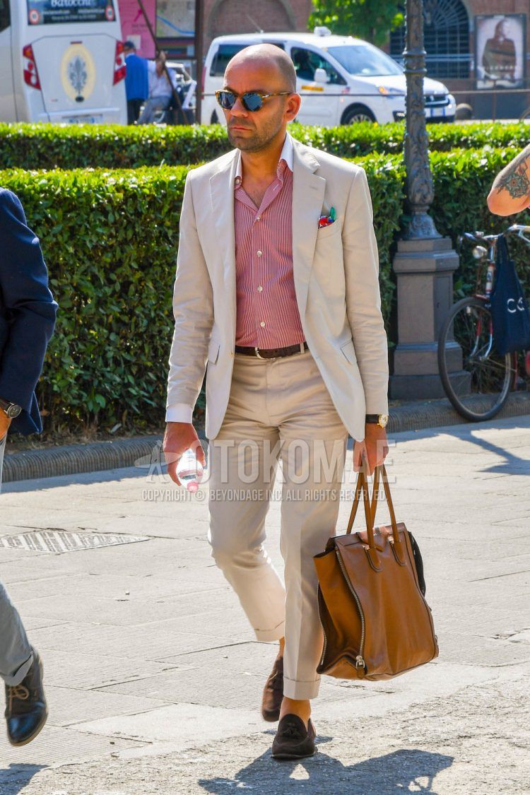 Spring, summer and fall men's coordinate outfit with tortoiseshell sunglasses, pink striped shirt, plain leather belt, brown tassel loafers leather shoes, brown suede shoes leather shoes, plain brown tote bag and plain beige suit.