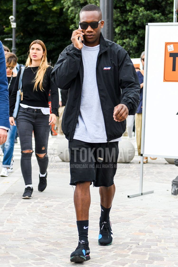 A summer/spring men's coordinate outfit with solid color sunglasses, solid color black windbreaker from Palace, solid color gray sweatshirt, solid color black shorts, solid color denim/jeans, solid color black socks from Nike, and black low-cut sneakers from Nike Off White The Ten.