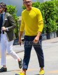 Spring and fall men's coordinate outfit with plain glasses, plain yellow sweater, plain navy cotton pants, and yellow/navy low-cut sneakers.