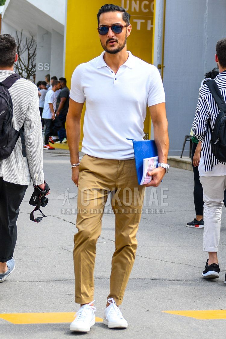 A summer men's coordinate outfit with plain sunglasses, a plain white polo shirt, plain beige chinos, and white low-cut sneakers.