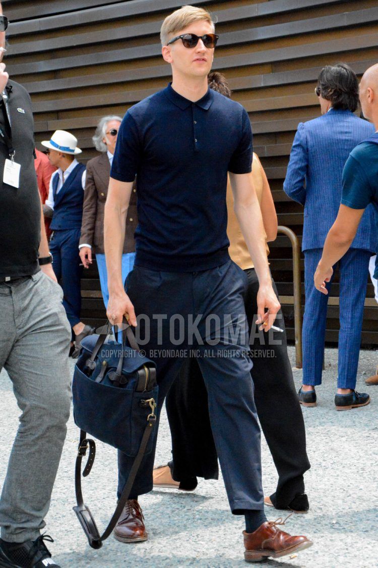 A summer/spring men's outfit with plain sunglasses, plain navy polo shirt, plain navy slacks, plain navy socks, brown plain-toe leather shoes, and plain shoulder bag.