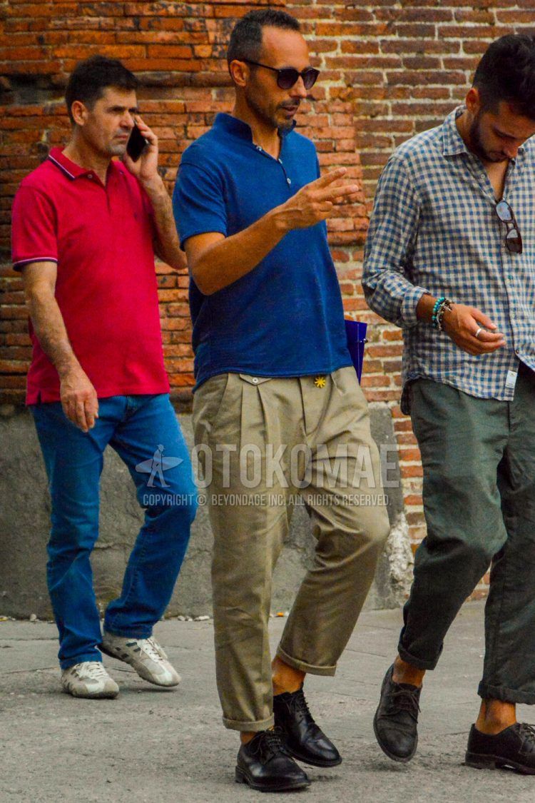 A men's spring/summer outfit with plain sunglasses, a plain blue polo shirt, plain beige slacks, and black plain-toe leather shoes.