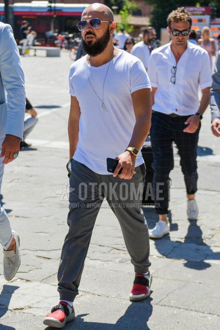 A summer men's coordinate outfit with plain silver sunglasses, plain white t-shirt, plain gray jogger pants/ribbed pants, plain white socks, and red low-cut sneakers.