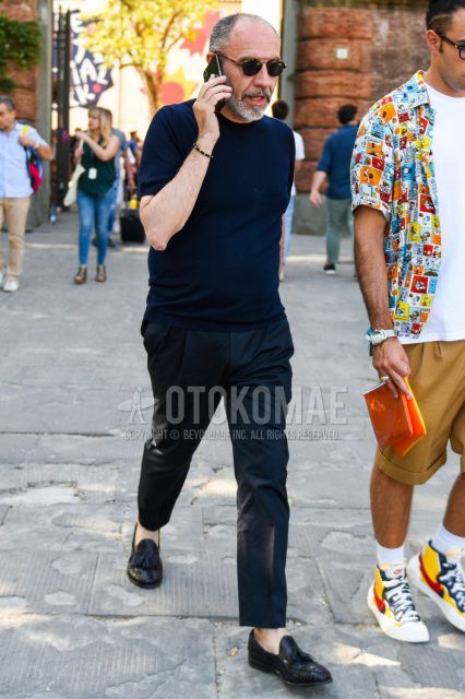 Summer men's coordinate outfit with black tortoiseshell sunglasses, plain navy t-shirt, plain black ankle pants, and black tassel loafer leather shoes.