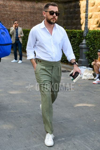 A spring/summer men's coordinate outfit with plain black sunglasses, plain white shirt, plain olive green beltless pants, plain pleated pants, and white low-cut sneakers.