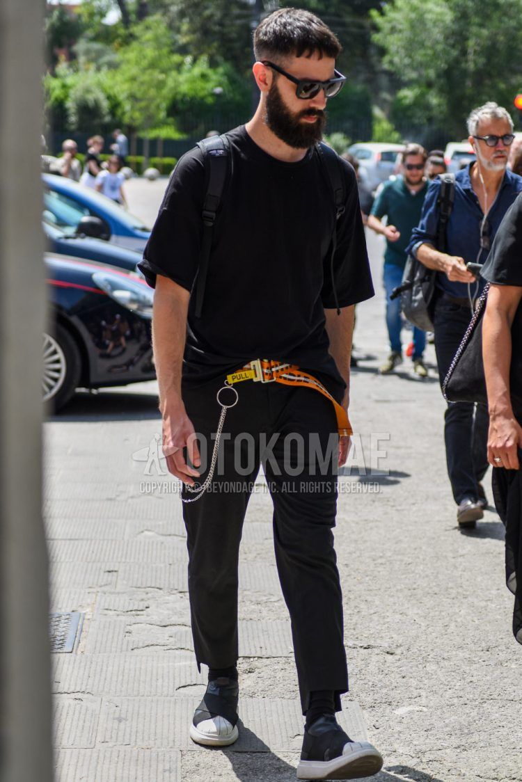 Summer men's coordinate outfit with plain black Wellington sunglasses, plain black t-shirt, orange or other tape belt, plain black other, plain black socks, and black high-cut sneakers.