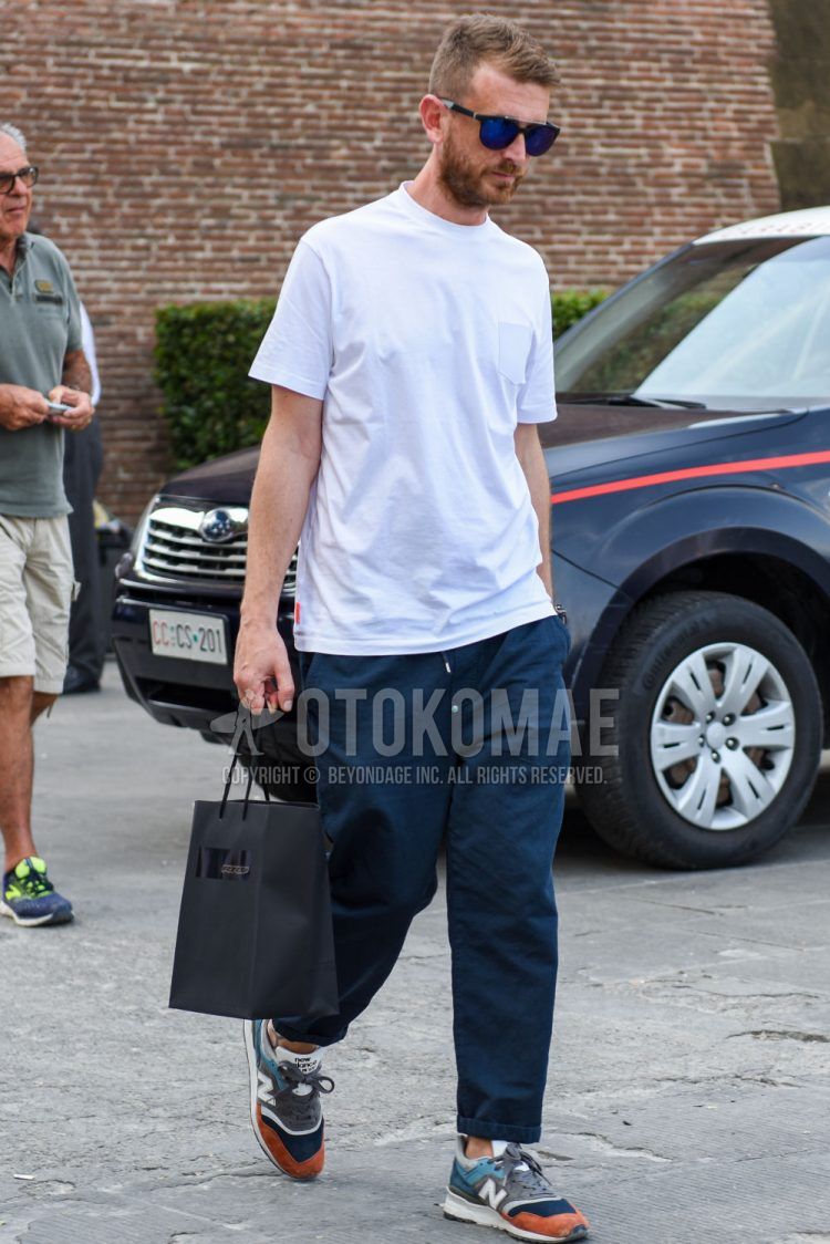 A summer men's coordinate outfit with Wellington plain black sunglasses, plain white t-shirt, plain navy easy pants, plain navy cotton pants, and New Balance multi-colored low-cut sneakers.