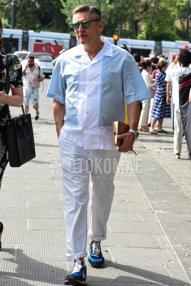 A summer men's coordinate outfit with plain black sunglasses, plain light blue/white shirt, plain white other, and Nike blue low-cut sneakers.