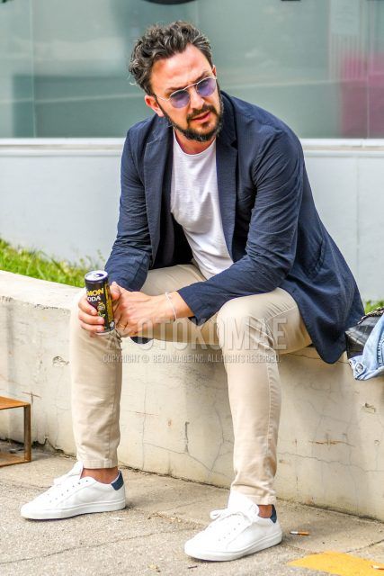 A summer/spring/fall men's coordinate outfit with plain sunglasses, plain navy tailored jacket, plain white t-shirt, plain beige ankle pants, and white low-cut sneakers.