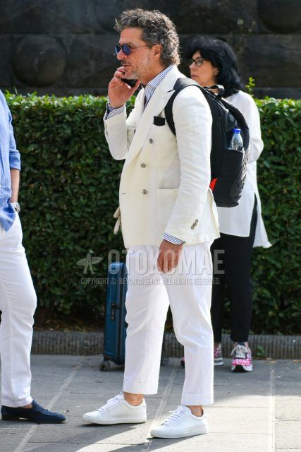 Men's spring, fall, and summer coordinate outfit with plain sunglasses, plain white tailored jacket, white/blue striped shirt, plain white cotton pants, and white low-cut sneakers.