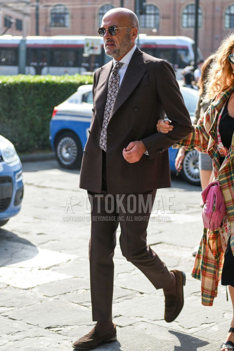 Spring and fall men's coordinate outfit with plain gold sunglasses, plain white shirt, plain brown socks, brown coin loafer leather shoes, plain brown suit, and brown paisley tie.