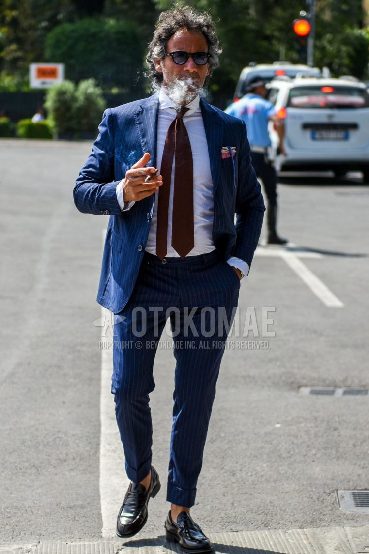 Spring and fall men's coordinate outfit with plain black sunglasses, plain white shirt, black coin loafer leather shoes, plain navy suit, and plain brown tie.