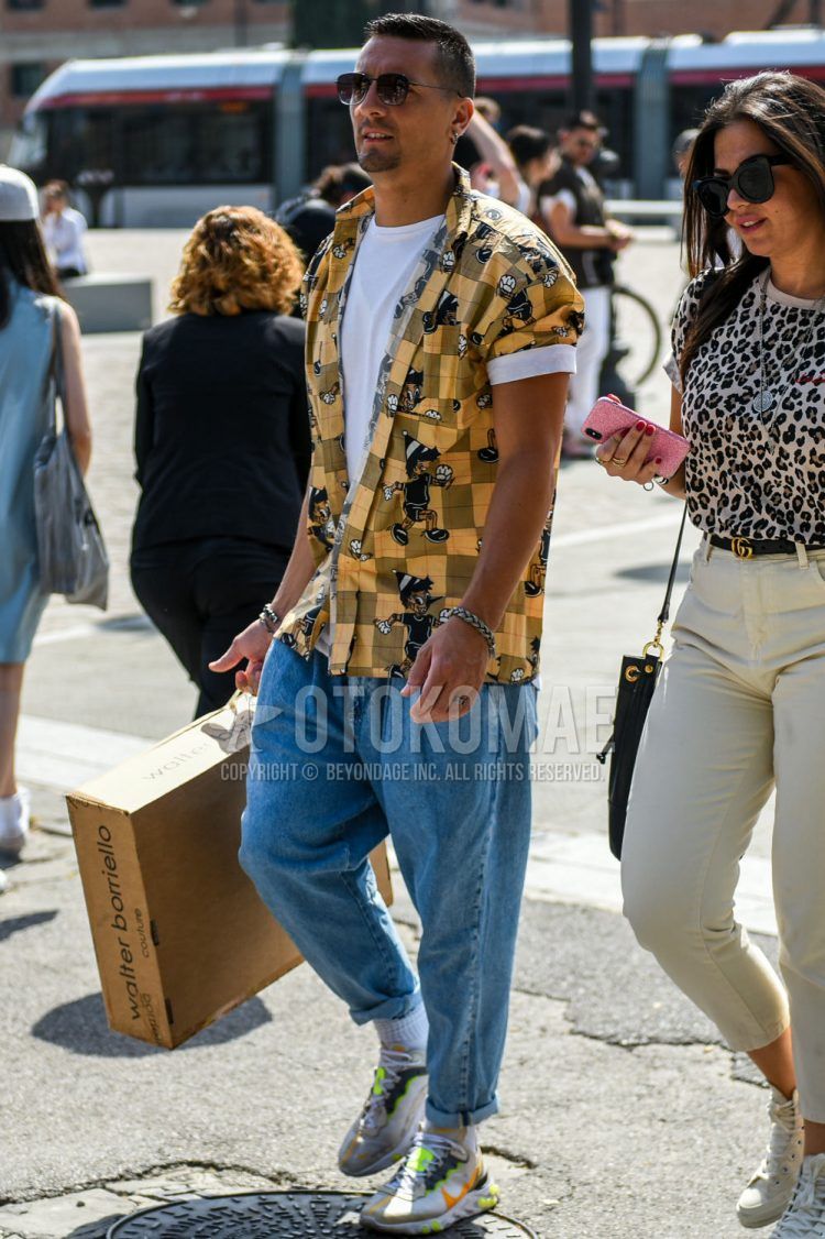 Spring and fall men's coordinate outfit with solid black sunglasses, solid yellow shirt, solid white t-shirt, solid blue denim/jeans, solid white socks, and Nike multi-colored low-cut sneakers.