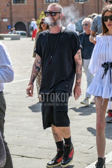 A summer men's coordinate outfit with plain black sunglasses, plain black t-shirt, plain black shorts, plain white socks, and Nike black and red high-cut sneakers.