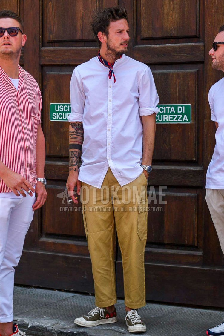 Spring/summer men's coordinate outfit with plain red bandana/neckerchief, plain white shirt, plain beige cargo pants, and olive green low-cut sneakers.