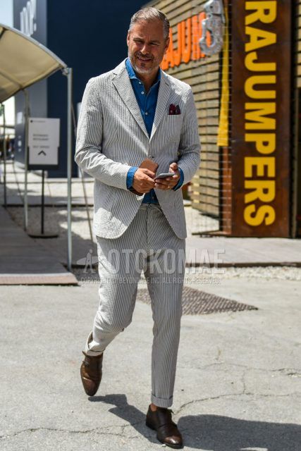A men's spring/fall/summer outfit with a plain blue denim/chambray shirt, brown monk shoe leather shoes, and a gray striped suit.