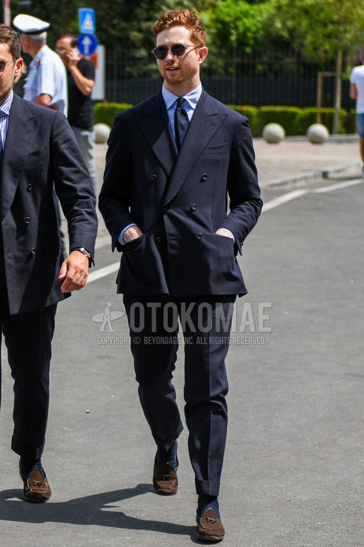A spring and fall men's outfit with clear solid sunglasses, light blue solid shirt, navy solid socks, brown suede shoes leather shoes, brown other loafer leather shoes, navy solid suit, and navy solid tie.