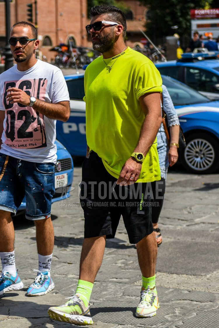 A summer men's coordinate outfit with solid black sunglasses, solid yellow t-shirt, solid black mesh belt, solid black shorts, solid yellow socks, and Nike yellow-cut sneakers.
