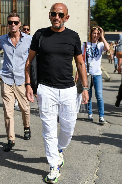 A summer men's coordinate outfit with plain sunglasses, a plain black t-shirt, plain white cotton pants, and white, green, and blue low-cut sneakers.