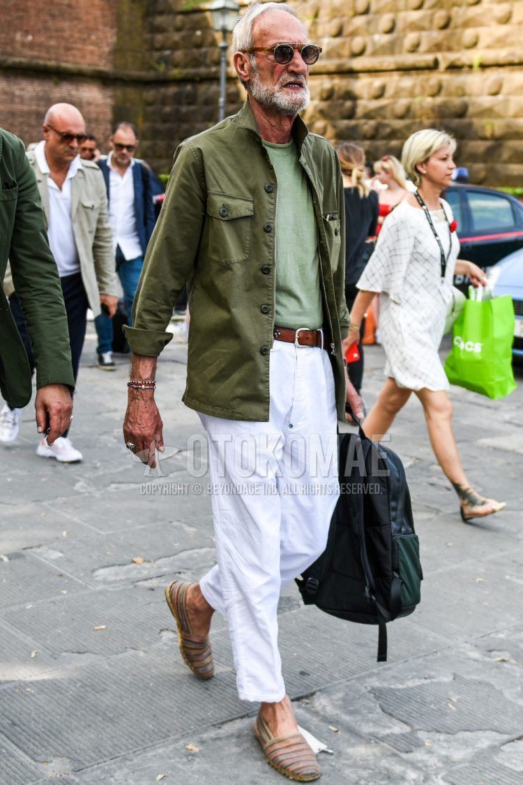 Spring and fall men's coordinate outfit with plain brown sunglasses, plain olive green shirt jacket, plain green t-shirt, plain brown leather belt, plain white cotton pants, and multi-colored espadrilles.