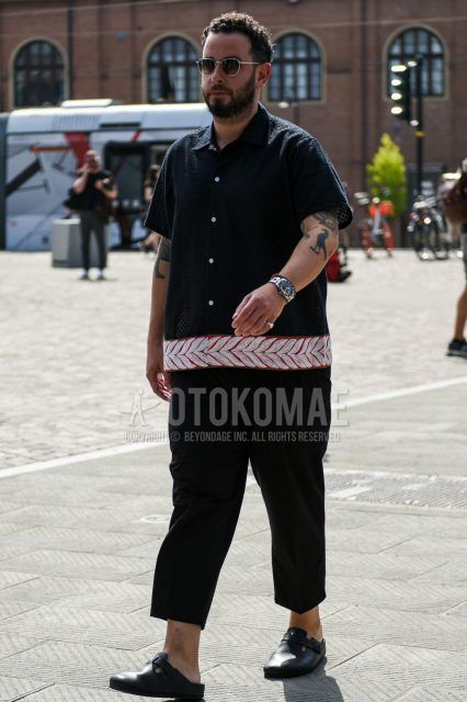 Summer men's coordinate outfit with plain silver sunglasses, short-sleeved black and other shirts, plain black/gray cropped pants, and black leather sandals.