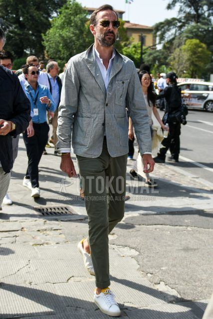 Spring, summer and fall men's coordinate outfit with beige tortoiseshell sunglasses, gray striped tailored jacket, plain white shirt, plain olive green chinos and white low-cut sneakers.