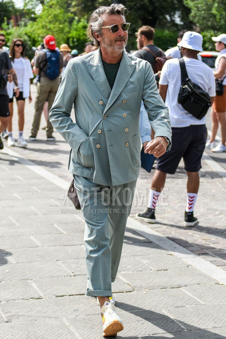 A spring/summer men's coordinate outfit with clear solid color sunglasses, solid color gray t-shirt, Nike Air Tail Wind 79 white low-cut sneakers, and solid color gray/light blue suit.