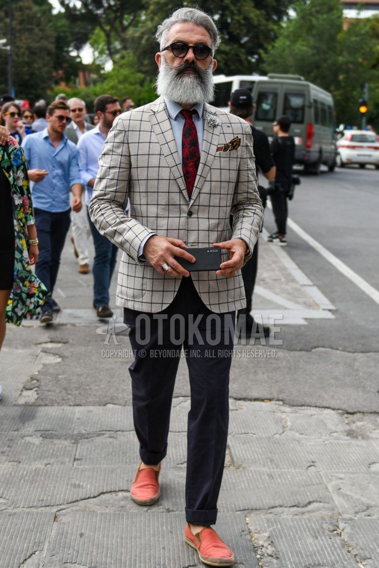 Men's spring/summer/fall outfit with plain black sunglasses, beige checked tailored jacket, plain gray shirt, plain gray slacks, plain orange/red espadrilles, and red botanical tie.