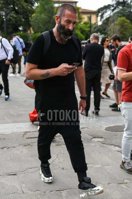 A summer men's coordinate outfit with a plain black t-shirt, plain black jogger pants/ribbed pants, and Raf Simons Oswego black and silver low-cut sneakers.