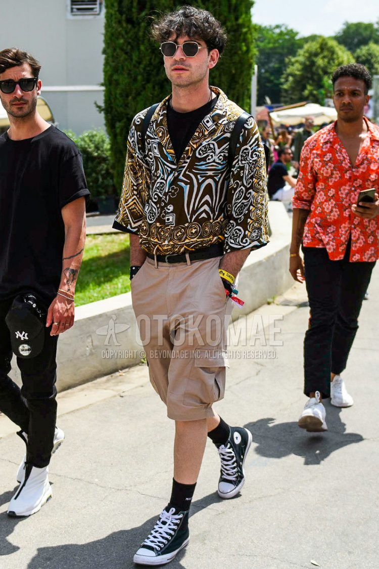 Black and gold solid color sunglasses, quarter sleeve open collar multi-colored other shirt, solid color black t-shirt, solid color black leather belt, solid color beige cargo pants, solid color shorts, solid color black socks, and Converse All Star black high cut sneakers for spring and summer. Men's coordinate outfit.