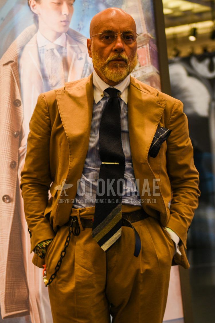 Spring, summer and fall men's coordinate outfit with plain silver glasses, light blue striped shirt, plain black leather belt, plain brown suit and black other tie.