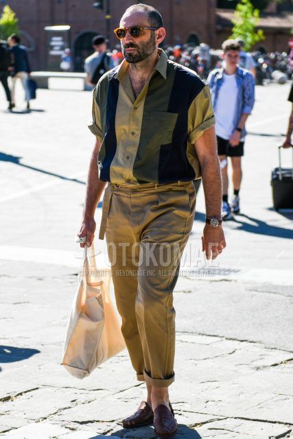 Spring and summer men's coordinate outfit with brown clear solid color sunglasses, short sleeved beige, black and olive green solid color shirt, beige solid color chinos and brown leather sandals.