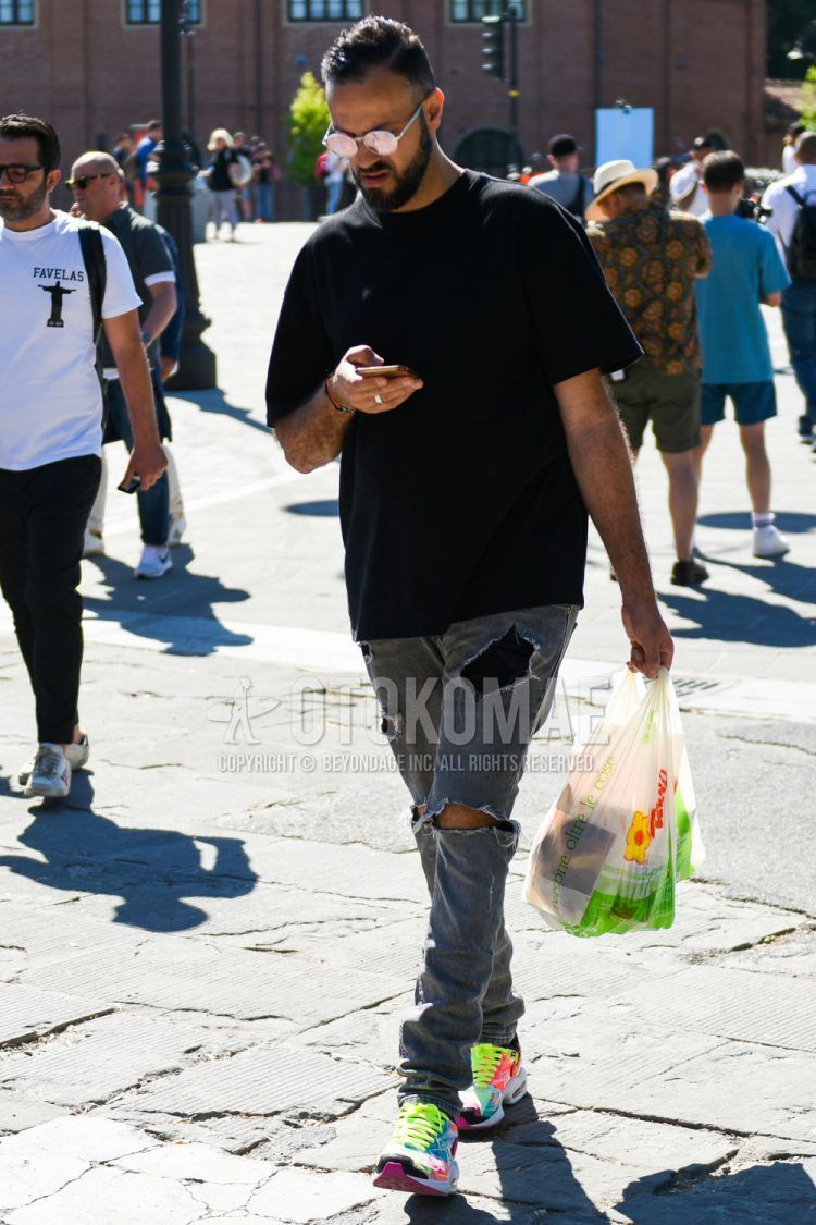 A summer men's coordinate outfit with round plain silver sunglasses, plain black t-shirt, plain gray damaged jeans, and Nike Atmos Air Max 2 Light multi-colored low-cut sneakers.