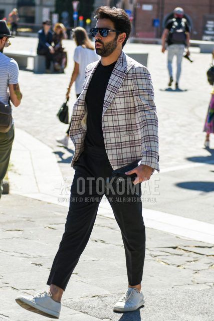 A men's spring/summer/fall outfit for men with plain black sunglasses, white checked tailored jacket, plain black t-shirt, plain gray slacks, plain ankle pants, and white low-cut sneakers.