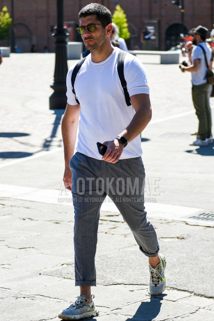 A summer men's coordinate outfit with plain black sunglasses, plain white t-shirt, gray stripes, and white low-cut Nike sneakers.