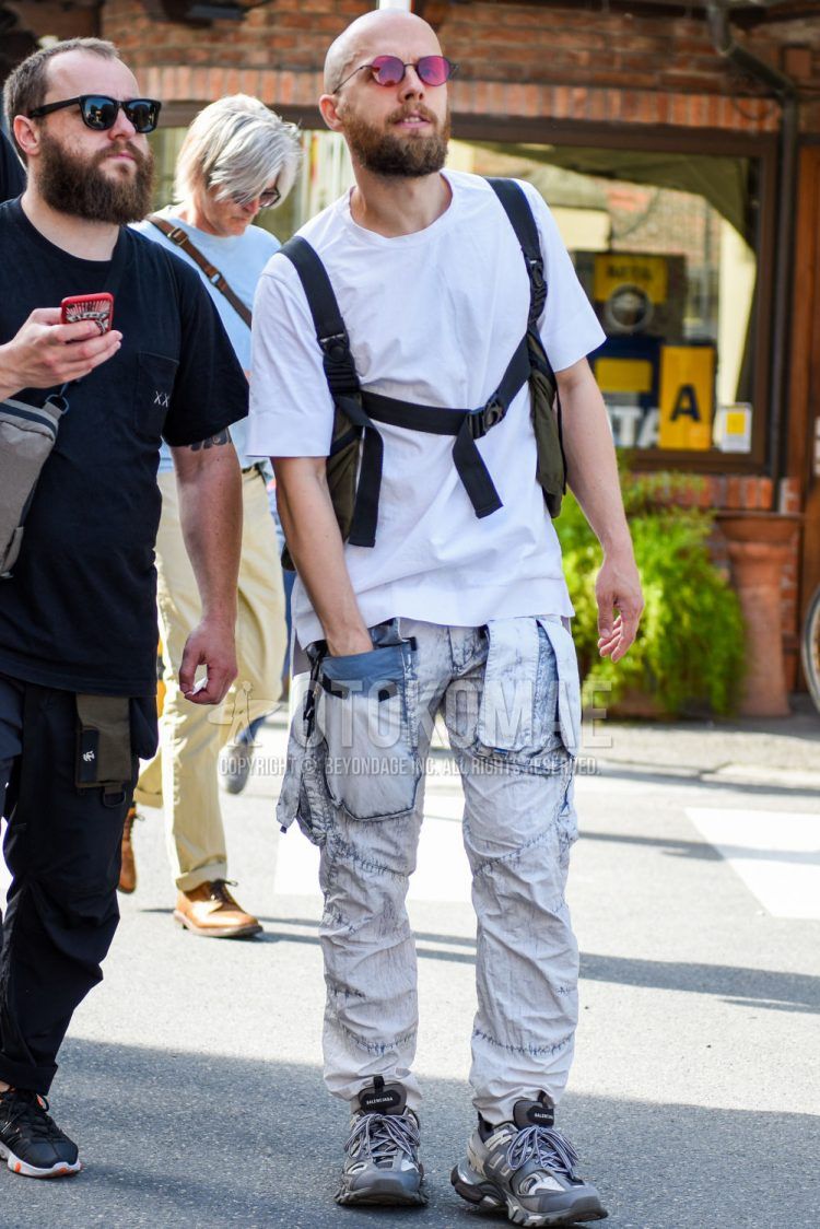 A summer men's coordinate outfit with a plain white T-shirt, plain white cotton pants, and gray low-cut sneakers.
