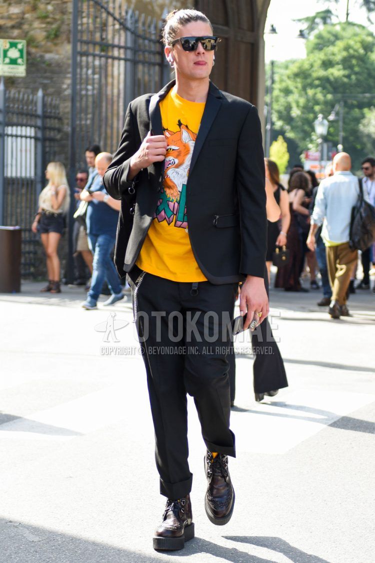 Wellington plain black sunglasses, yellow graphic t-shirt, brown and other boots, and plain black suit for men's spring, summer, and fall outfits.