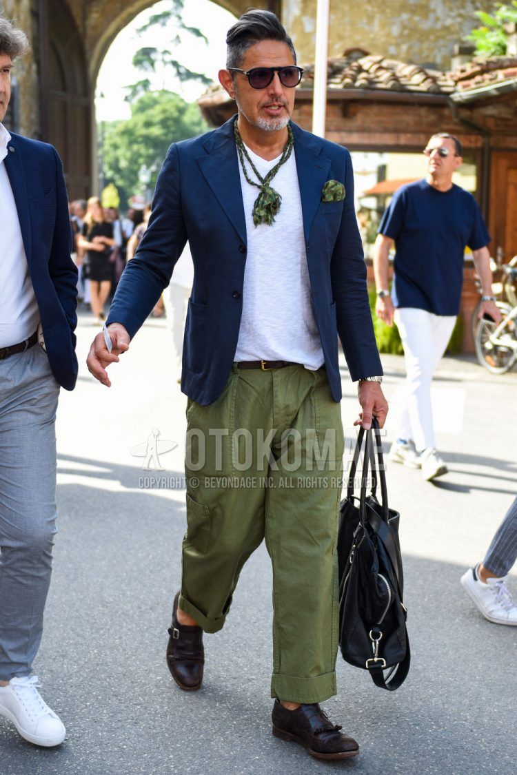 Spring, summer and fall men's coordinate outfit with plain black sunglasses, plain white t-shirt, plain brown leather belt, plain olive green wide pants, plain olive green cotton pants, brown monk shoes leather shoes and plain black tote bag.