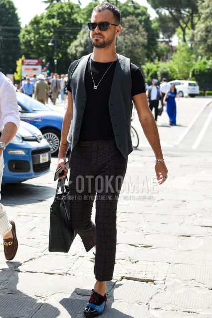 A summer men's outfit with a plain gray gilet, plain black t-shirt, dark gray check ankle pants, multi-colored other leather shoes, and a Louis Vuitton plain black tote bag.