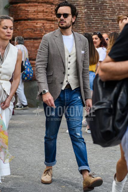 Spring, summer and fall men's coordinate outfit with black and brown tortoiseshell sunglasses, gray and brown checked tailored jacket, plain white t-shirt, plain white and beige gilet, plain blue damaged jeans and beige brogue shoes leather shoes.