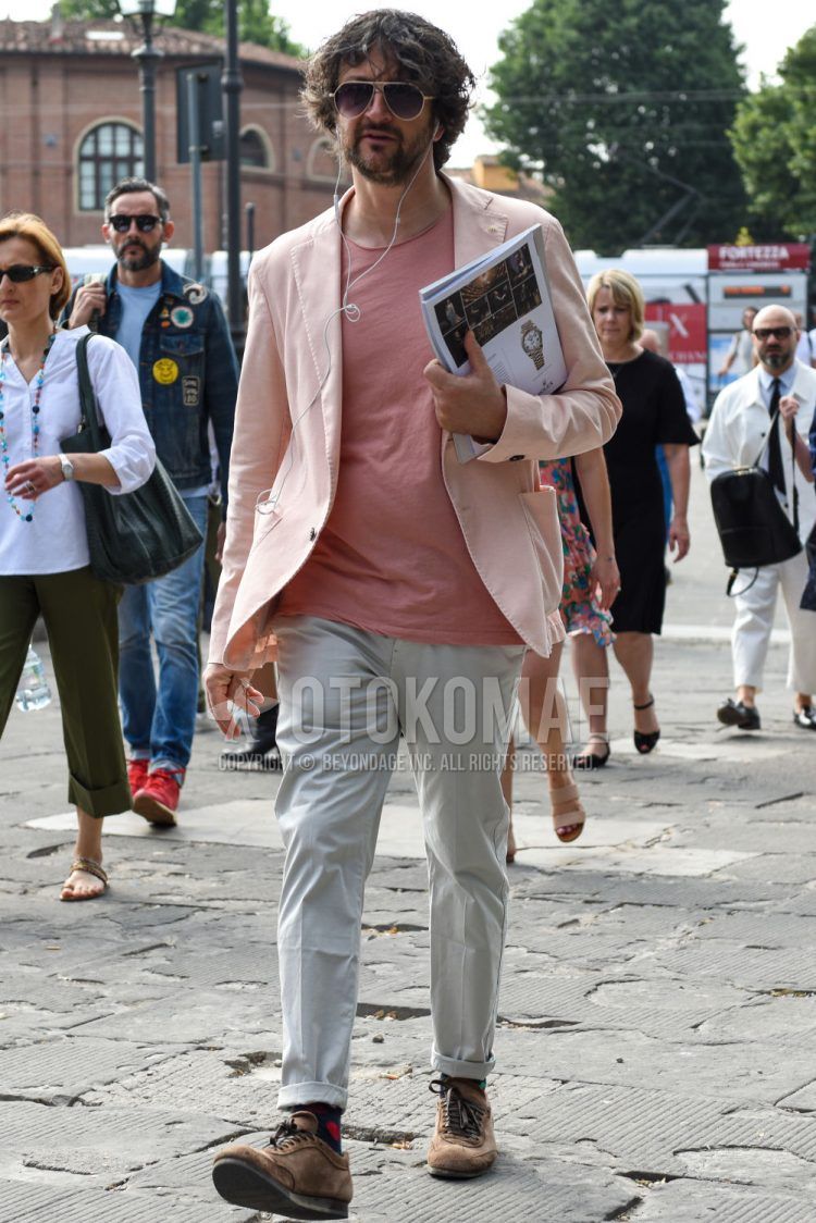 Spring, summer and fall men's coordinate outfit with teardrop gold solid sunglasses, pink solid tailored jacket, pink solid t-shirt, white solid cotton pants, navy solid socks and brown low-cut sneakers.