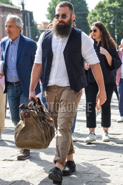 A spring/summer men's coordinate outfit with round black/gold solid sunglasses, solid navy gilet, solid white linen shirt, solid beige chinos, black plain toe leather shoes, and solid beige Boston bag.