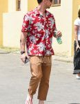 Summer men's coordinate outfit with plain black sunglasses, red botanical shirt, plain brown cotton pants, and open-collar red slip-on sneakers.