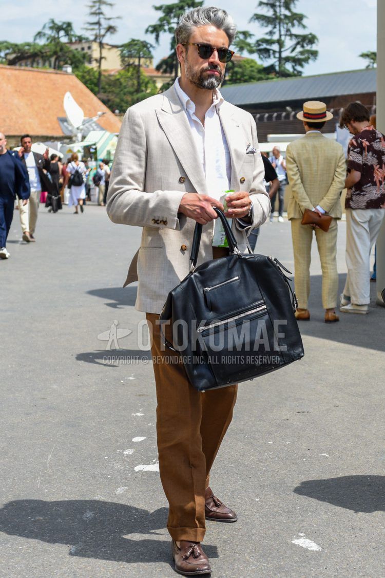 Men's spring/summer/fall outfit with black tortoiseshell sunglasses, plain white tailored jacket, plain white shirt, plain brown slacks, brown tassel loafer leather shoes, and plain black briefcase/handbag.